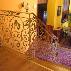 A wrought iron white railing with gold-green patina
