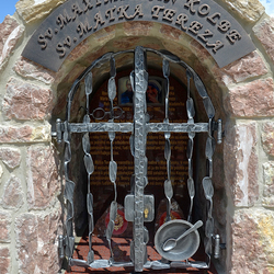 Kovaný pamätník. Sv. Maximilián Kolbe - okuliare, Sv. Matka Tereza - miska s lyžicou
