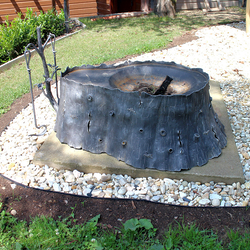 Artistic fireplace forged as a stump of a tree with oak fireplace tools