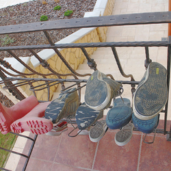 A wrought-iron railing by the entrance of a family house with forged shoe-rack