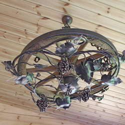 An exceptional hand wrought chandelier of a vine design is forged into the wagon wheel