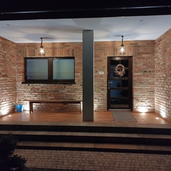 Večerný pohľad na osvetlený vstup do rodinného domu - kované exteriérové svietidlá