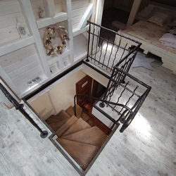 Pohľad na vstup do podkrovia - kované schodisko s drevenými stúpačkami a zábradlím